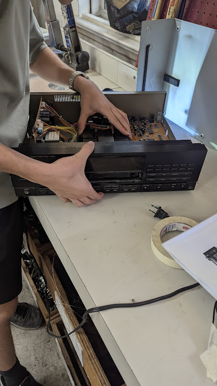 My friend, holding the CD tray in his left hand and the whole assembly with his right hand, trying to remove the former from the latter.