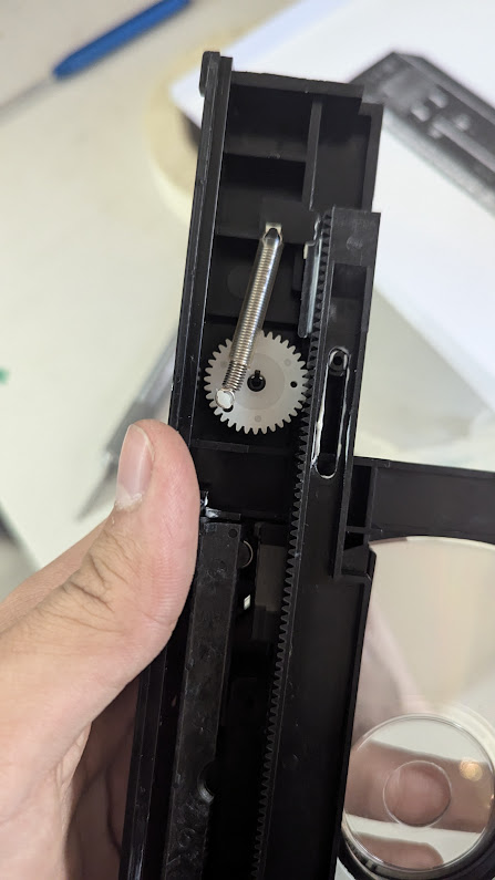 A spring connected to a gear and the plastic panel which it's installed on. It's protected by some tubing.
